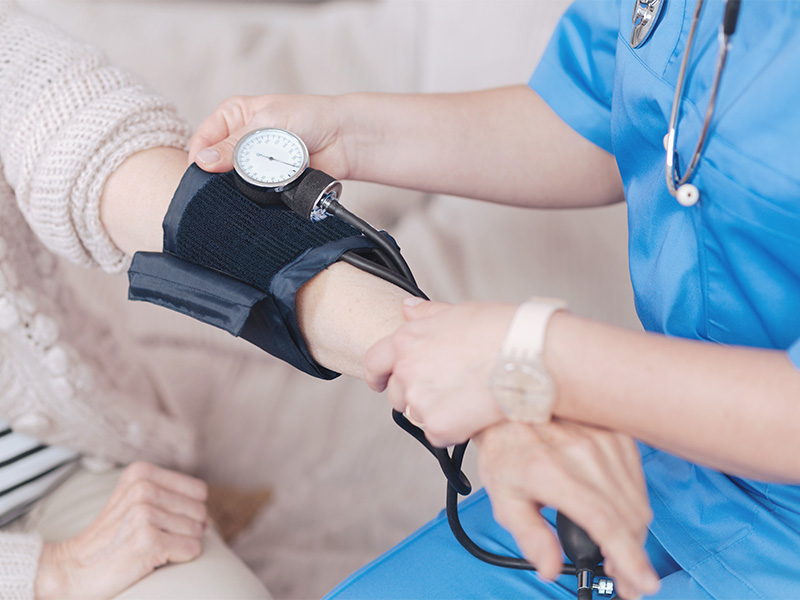 Pflegekraft misst Blutdruck einer Seniorin zu Hause und unterstützt die medizinische Versorgung im ambulanten Pflegedienst in Nettersheim.