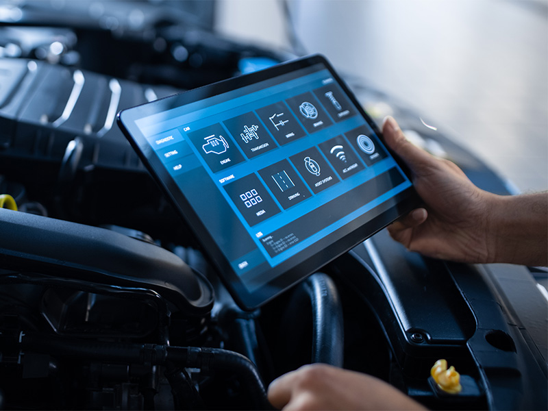 Mechaniker nutzt Tablet zur Diagnose während Hauptuntersuchung in Schleiden, überprüft Fahrzeugkomponenten im Motorraum systematisch