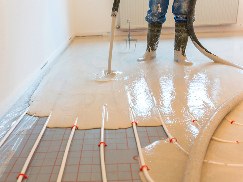 Verlegung von Estrich auf Fußbodenheizung im Neubau mit sichtbaren Heizrohren und vorbereitetem Bodenaufbau.