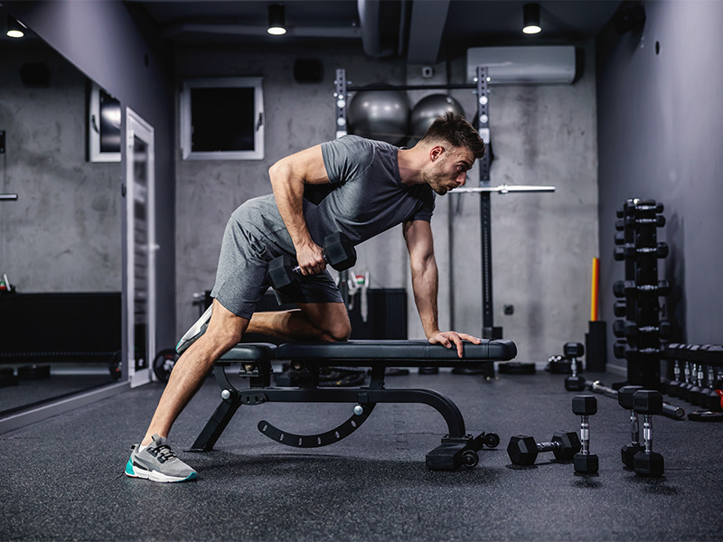 Muskulöser Mann trainiert mit Kurzhantel auf Trainingsbank beim intensiven Krafttraining in Euskirchen im modernen Fitnessstudio