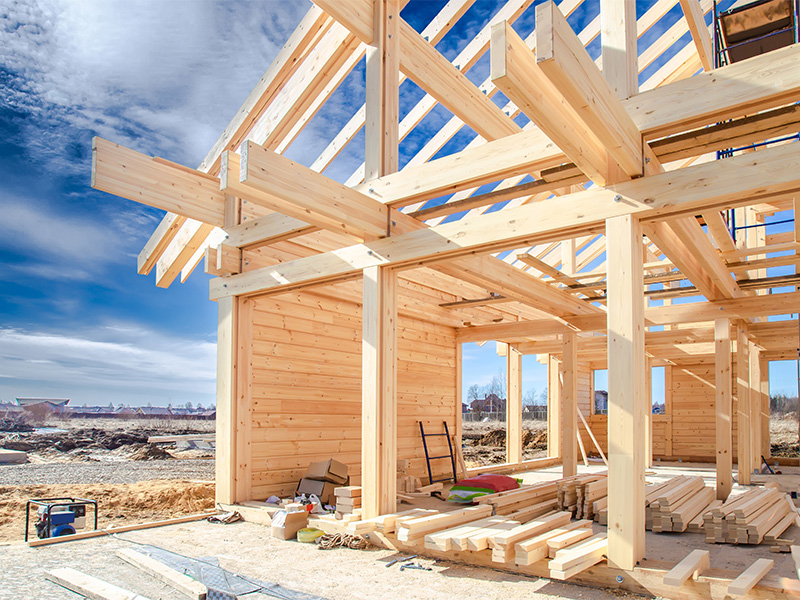 Holzbau eines Einfamilienhauses mit sichtbarer Rahmenkonstruktion auf Baustelle während der Errichtung des Rohbaus