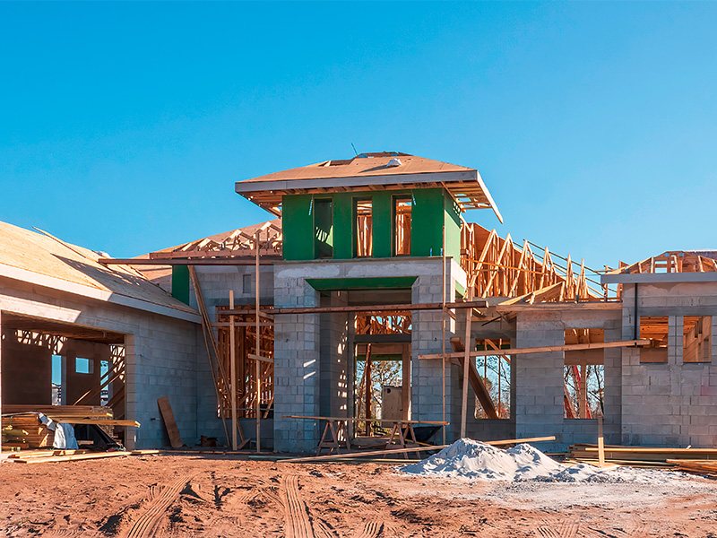 Neubau eines Einfamilienhauses mit Holzkonstruktion, Baumaterialien und offenem Dachbereich in moderner Wohnsiedlung bei sonnigem Wetter