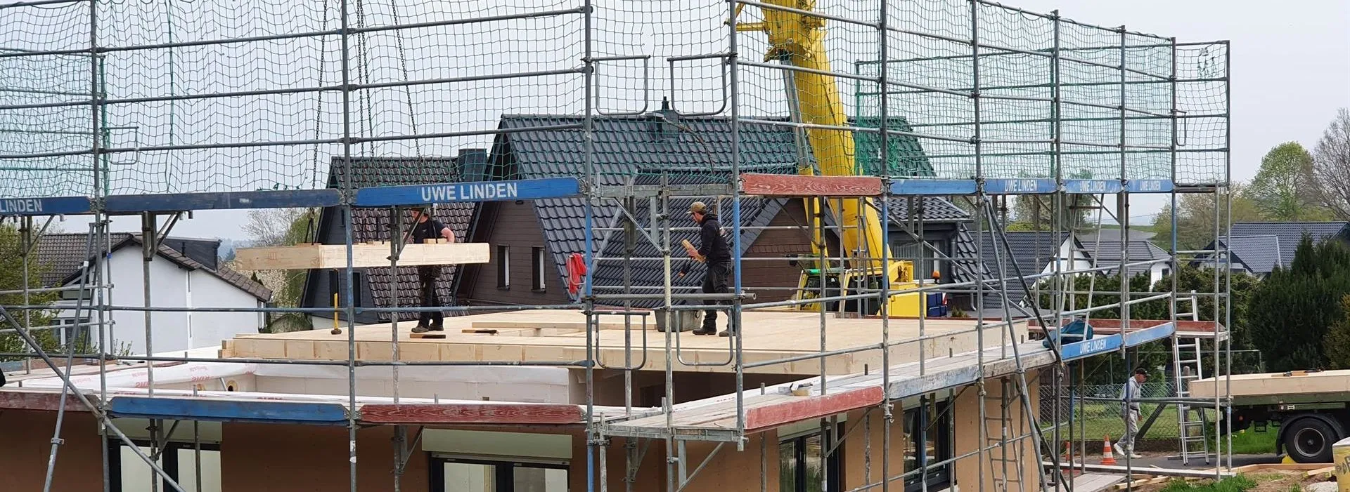 Innenansicht eines Holzrahmenbaus mit sichtbaren Holzbalken und Dachkonstruktion im Rohbau eines modernen Hauses.