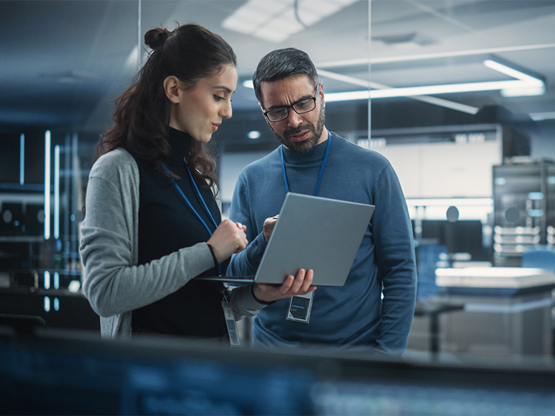 Zwei Ingenieure analysieren IT Sicherheit und künstliche Intelligenz Software am Laptop in moderner High-Tech Büro Umgebung
