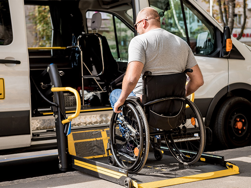 Mann im Rollstuhl nutzt Hebebühne für sicheren Rollstuhltransport per Taxi in Blankenheim zu medizinischen Terminen.