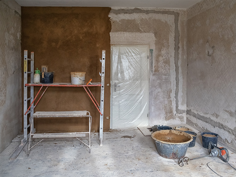 Handwerker verarbeitet ökologischen Wandputz vom Profi auf einer Innenwand während einer nachhaltigen Renovierung mit natürlichen Materialien und strukturierter Oberfläche.
