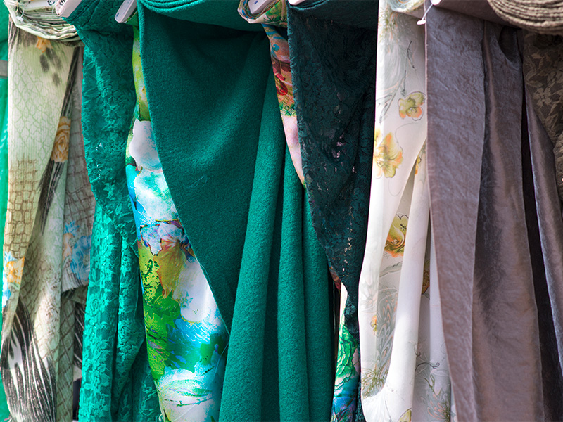 Verschiedene Stoffbahnen in harmonischen Farben, sorgfältig angeordnet, als Auswahlmöglichkeit für hochwertige Gardinen nach Maß.