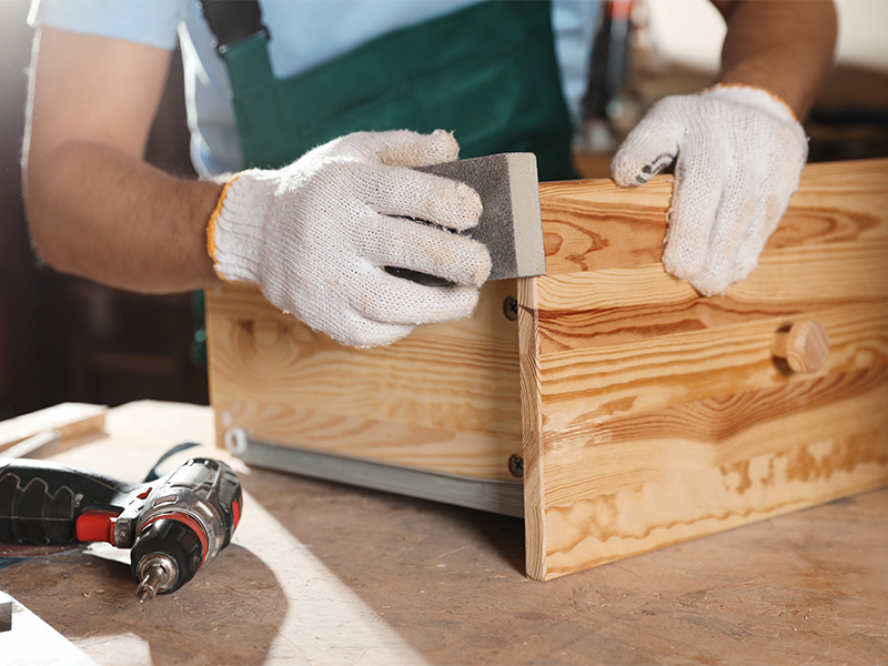 Schreiner poliert und bearbeitet Holzschublade für maßgefertigten Einbauschrank in Werkstatt