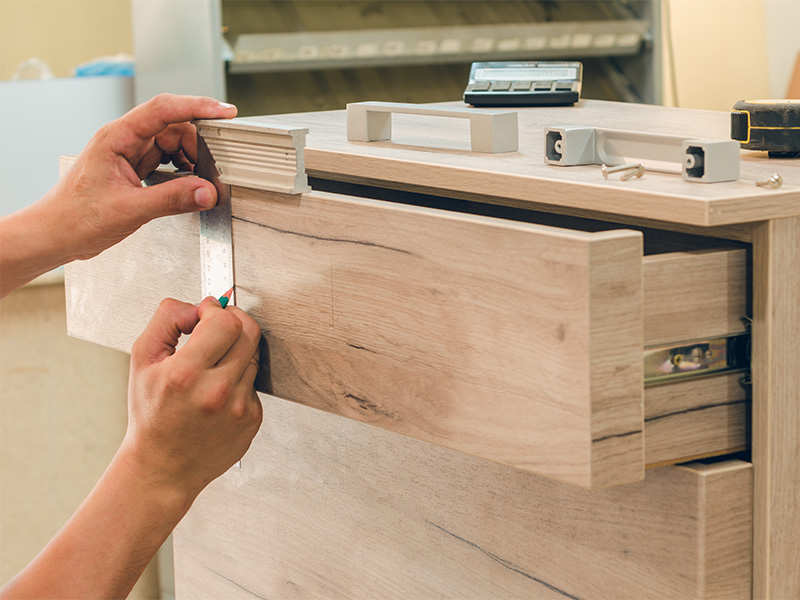 Handwerker montiert Möbel nach Maß in Euskirchen, befestigt präzise Schrauben und passt Einbaumöbel sorgfältig an.