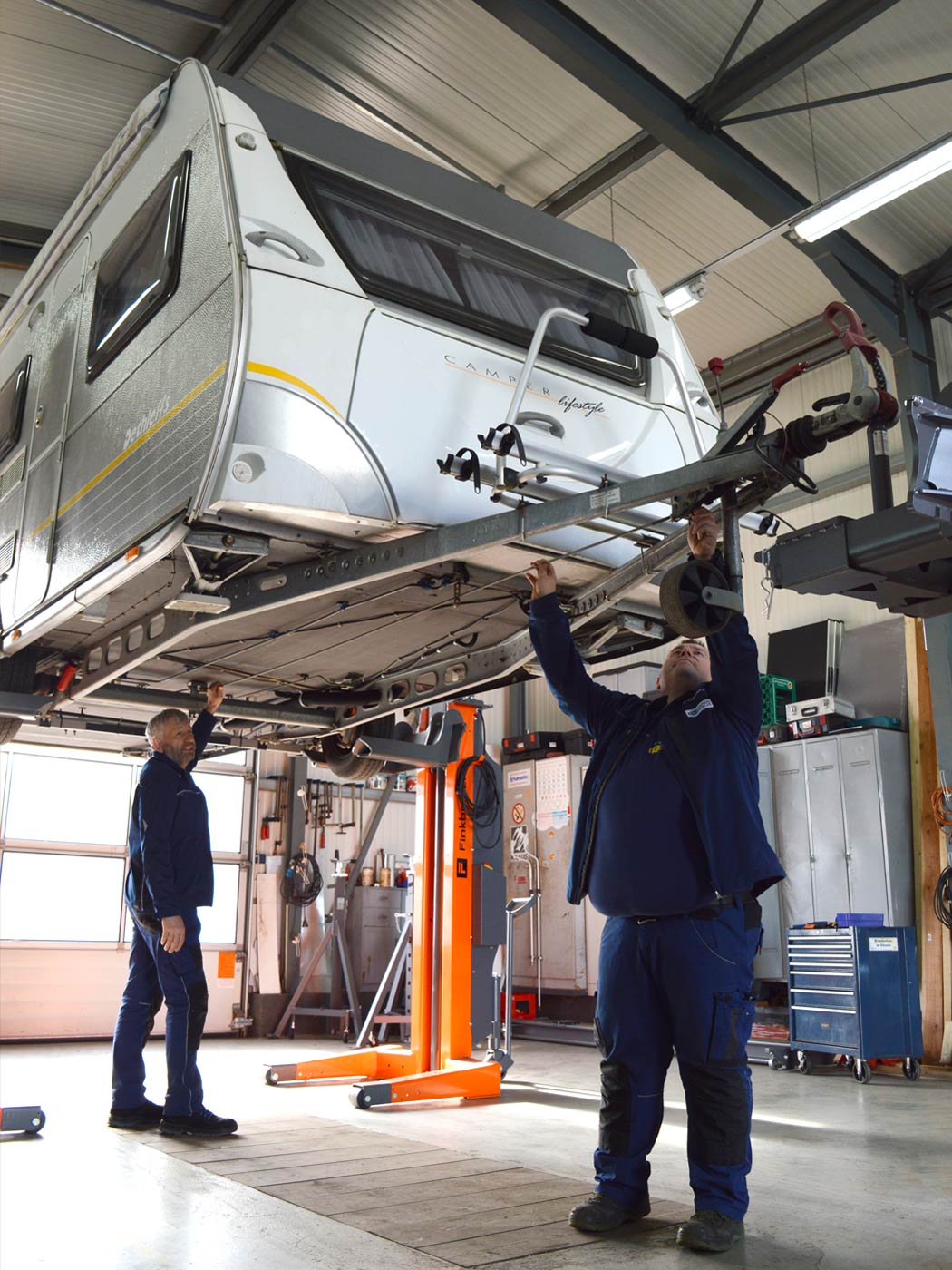 Hebeb&uuml;hne in Werkstatt mit angehobenem Fahrzeug bei Wartungs- und Reparaturarbeiten im Rahmen der Wohnmobilreparatur in Schleiden