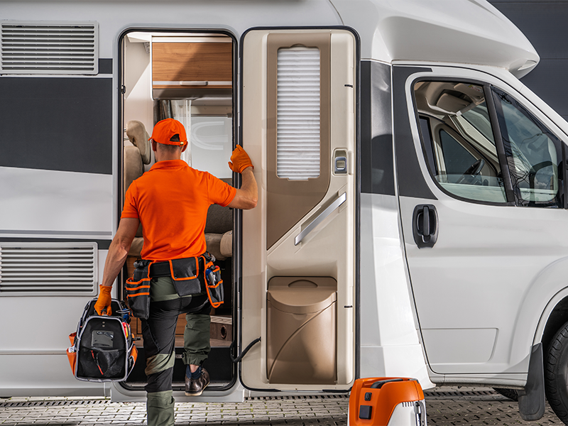 Techniker arbeitet an Wohnmobil-Eingang bei Reparatur in urbaner Umgebung w&auml;hrend professioneller Wohnmobilreparatur in Schleiden