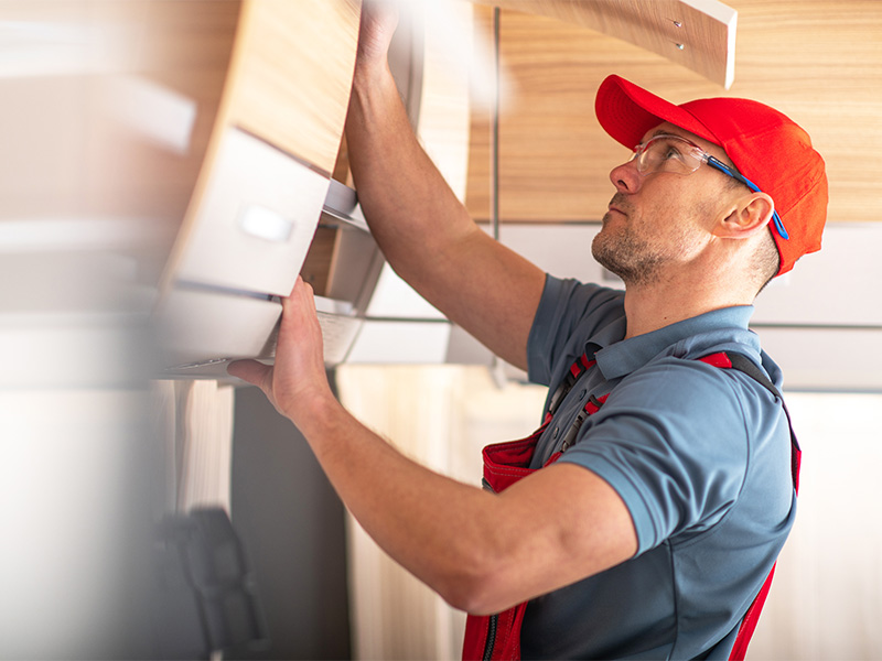 Handwerker installiert Regalsystem in modernem Innenraum w&auml;hrend Renovierungsarbeiten im hellen Tageslicht bei professioneller Wohnwagenreparatur